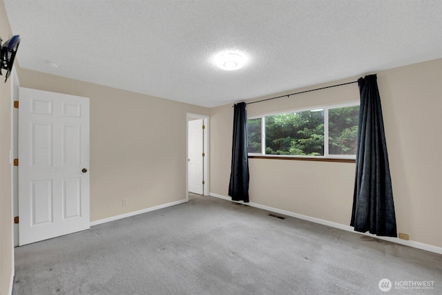 spare room with carpet, a textured ceiling, and baseboards