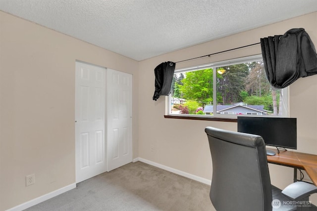 carpeted office space with a textured ceiling and baseboards