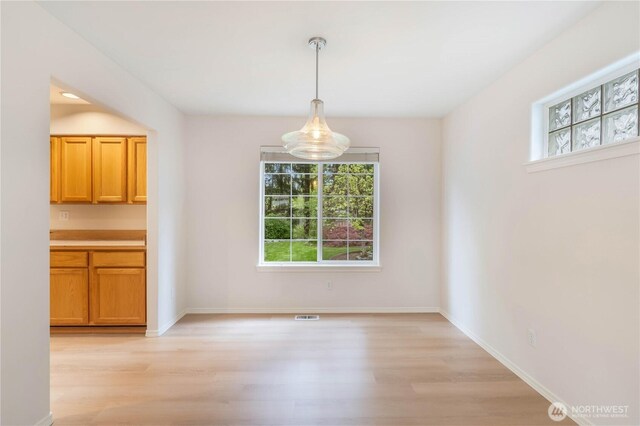 unfurnished dining area featuring light wood-style floors, baseboards, and visible vents
