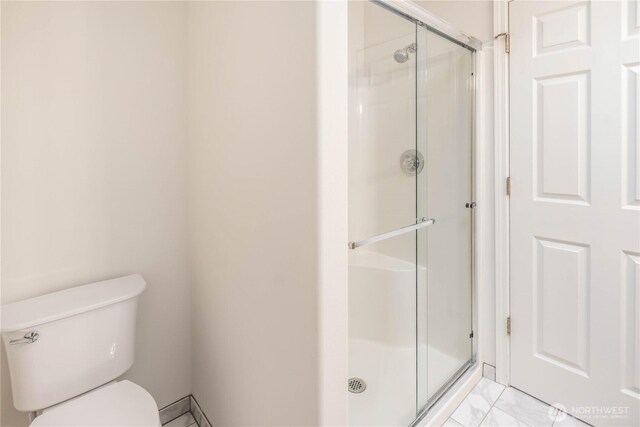 bathroom featuring toilet and a shower stall