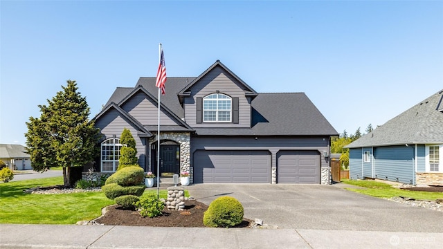 view of front of property with an attached garage, aphalt driveway, a front yard, and stone siding
