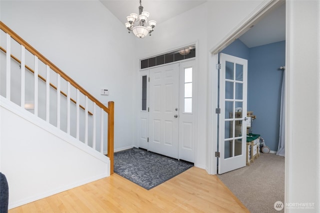 entrance foyer featuring baseboards, a chandelier, wood finished floors, and stairway
