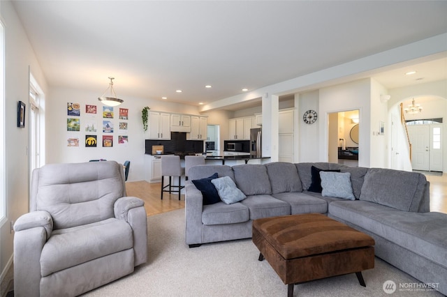 living area with recessed lighting, arched walkways, and light wood finished floors