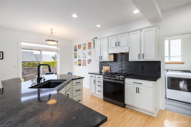 kitchen with a sink, gas stove, light wood finished floors, washer / clothes dryer, and under cabinet range hood