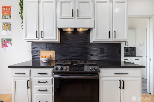 kitchen featuring stainless steel range with gas stovetop, dark countertops, decorative backsplash, and white cabinets
