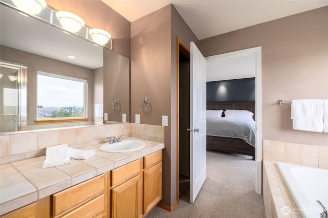 ensuite bathroom with a relaxing tiled tub, ensuite bathroom, and vanity