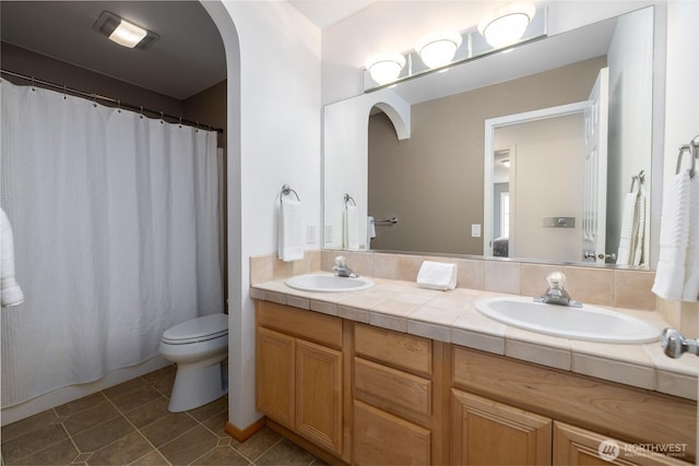full bathroom featuring double vanity, toilet, a sink, and tile patterned flooring
