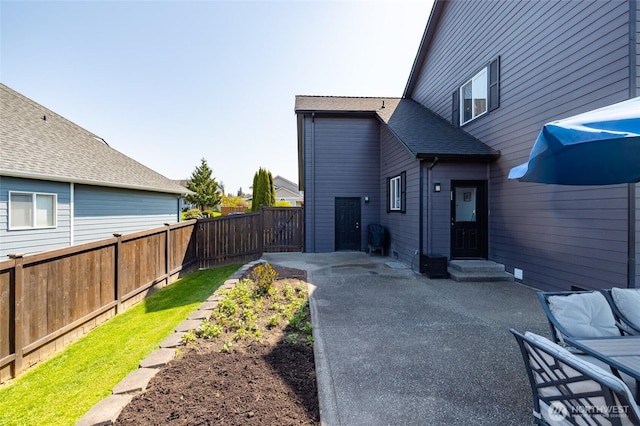 view of side of property featuring a patio, a shingled roof, a fenced backyard, and entry steps