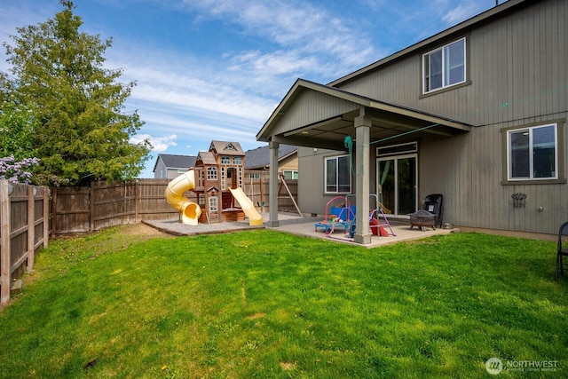 rear view of property featuring a playground, a patio, a yard, and a fenced backyard
