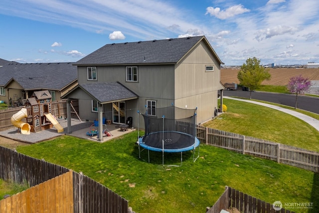 rear view of property featuring a yard, a playground, a trampoline, and a patio area