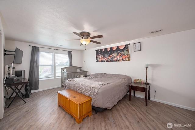 bedroom featuring visible vents, a ceiling fan, light wood-style flooring, and baseboards