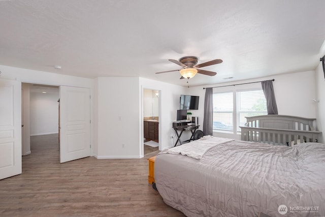 bedroom with baseboards, ceiling fan, wood finished floors, and connected bathroom