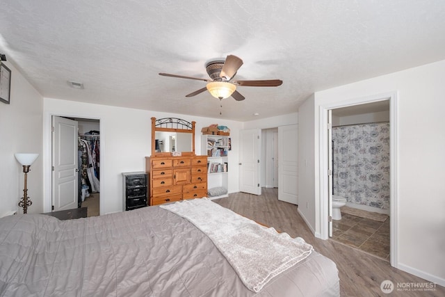 bedroom featuring visible vents, a closet, wood finished floors, baseboards, and a spacious closet