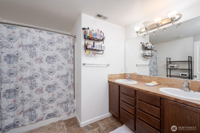 full bath featuring visible vents, double vanity, baseboards, and a sink