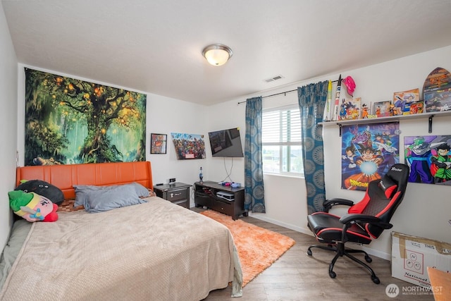 bedroom featuring baseboards, wood finished floors, and visible vents