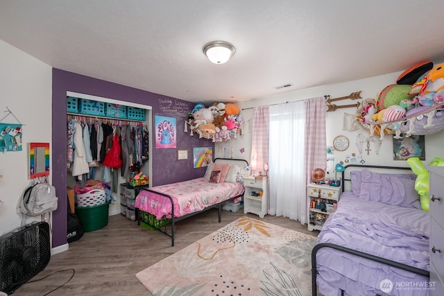 bedroom with a closet, wood finished floors, and visible vents