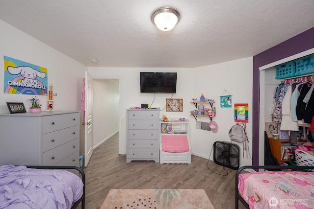 bedroom with a closet, baseboards, and wood finished floors