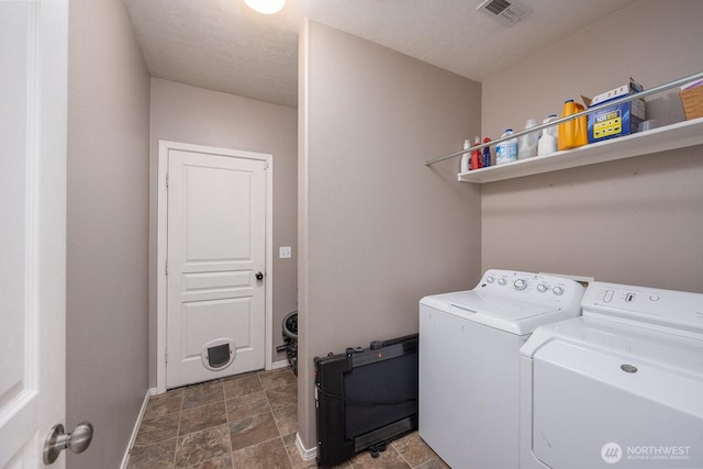 laundry area featuring washing machine and clothes dryer, laundry area, stone finish floor, baseboards, and visible vents