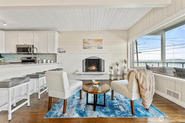 interior space with a water view, visible vents, wood finished floors, and a fireplace