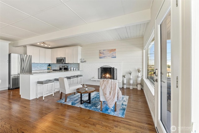 living area with beam ceiling, dark wood-style floors, and a fireplace