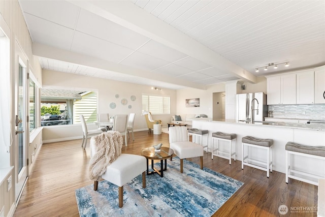 living area with wood finished floors and beam ceiling