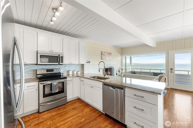 kitchen featuring a sink, light wood finished floors, stainless steel appliances, and a peninsula