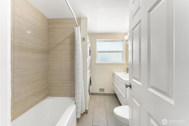 bathroom featuring vanity, visible vents, stacked washer / dryer, toilet, and tile patterned floors