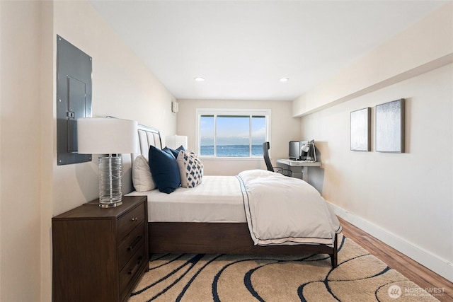 bedroom featuring recessed lighting, baseboards, light wood-style flooring, and electric panel