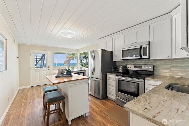 kitchen featuring light wood-style flooring, appliances with stainless steel finishes, a wealth of natural light, and wooden counters