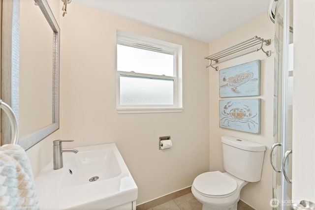 bathroom featuring baseboards, a sink, tile patterned flooring, and toilet