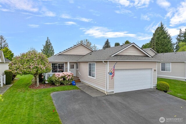 ranch-style home featuring roof with shingles, an attached garage, a front lawn, and aphalt driveway