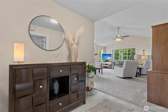 interior space featuring light wood-style flooring, a ceiling fan, light colored carpet, and lofted ceiling