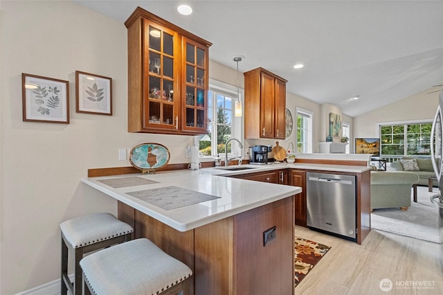 kitchen featuring a peninsula, glass insert cabinets, light countertops, a sink, and dishwasher