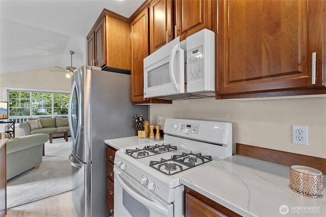 kitchen with lofted ceiling, white appliances, open floor plan, brown cabinets, and a ceiling fan