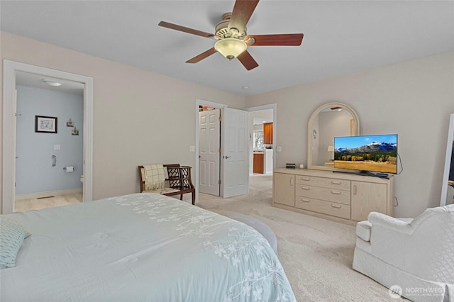 bedroom featuring light colored carpet, ceiling fan, and ensuite bath