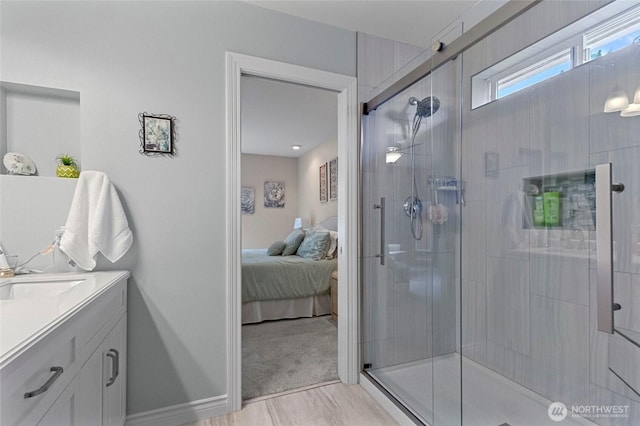 bathroom with vanity, connected bathroom, baseboards, and a shower stall