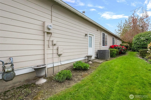 view of side of property featuring a lawn and cooling unit