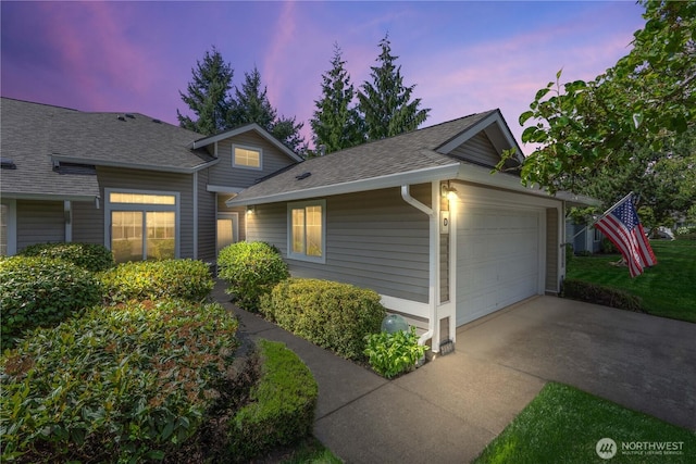 view of front of house with driveway, roof with shingles, and an attached garage