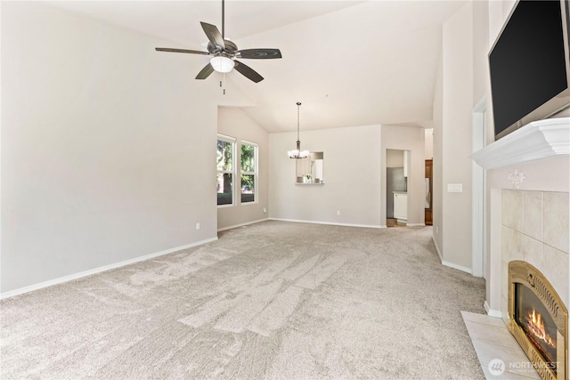 unfurnished living room with a tile fireplace, ceiling fan with notable chandelier, baseboards, light colored carpet, and vaulted ceiling