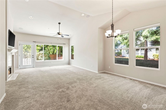 carpeted spare room with lofted ceiling, baseboards, visible vents, ceiling fan with notable chandelier, and a fireplace with flush hearth