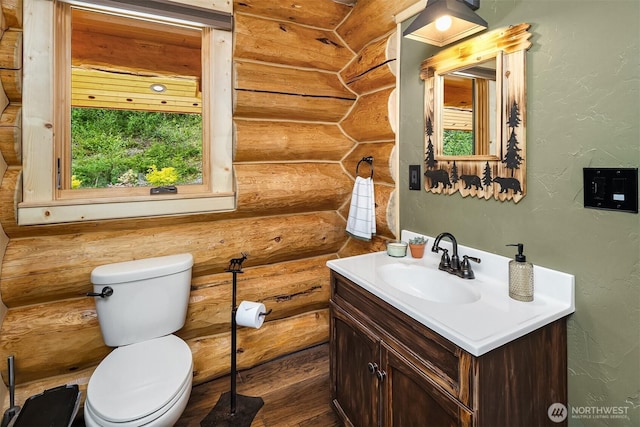 bathroom featuring toilet, a textured wall, log walls, and vanity