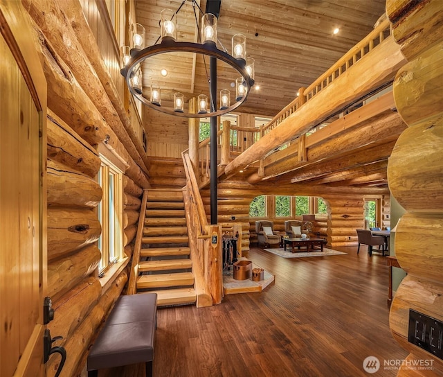 interior space featuring a notable chandelier, wood-type flooring, wooden ceiling, a towering ceiling, and log walls