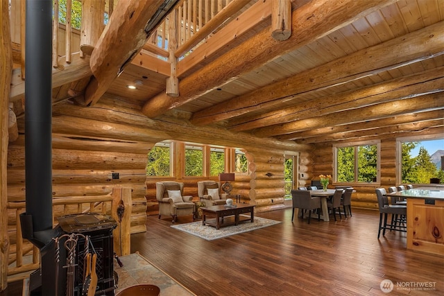 living room with wood ceiling, a wood stove, beam ceiling, dark wood-style floors, and log walls