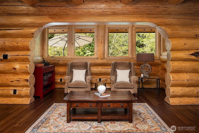 sitting room with arched walkways and dark wood-style flooring