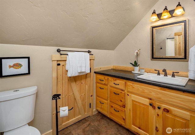 bathroom featuring vanity, vaulted ceiling, and toilet