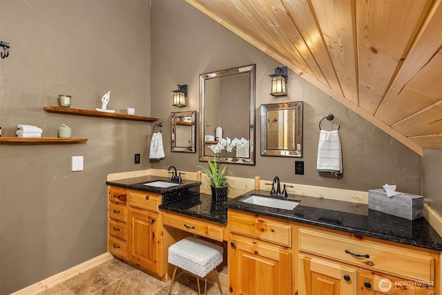 bathroom featuring a sink, wood ceiling, double vanity, and lofted ceiling