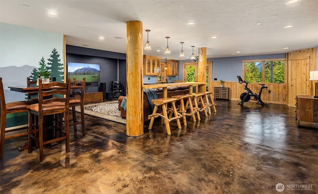 dining space featuring indoor bar, recessed lighting, concrete floors, and wooden walls