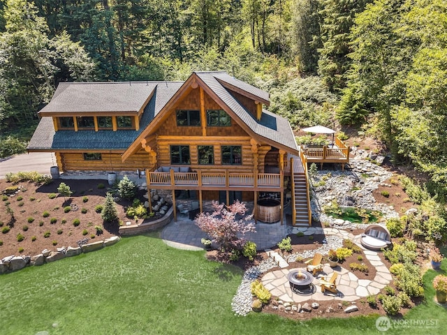 rear view of property with log exterior, a fire pit, stairs, and a deck