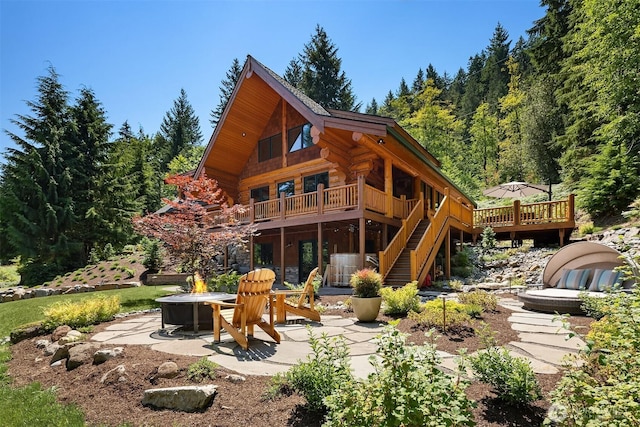 rear view of house featuring a fire pit, a deck, a patio, stairs, and log siding