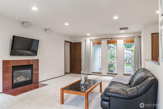 carpeted living area featuring recessed lighting, visible vents, and a tiled fireplace